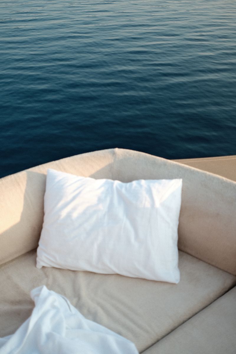 Soft white pillow on a luxury yacht seat alongside a tranquil ocean view, perfect for a relaxing getaway.